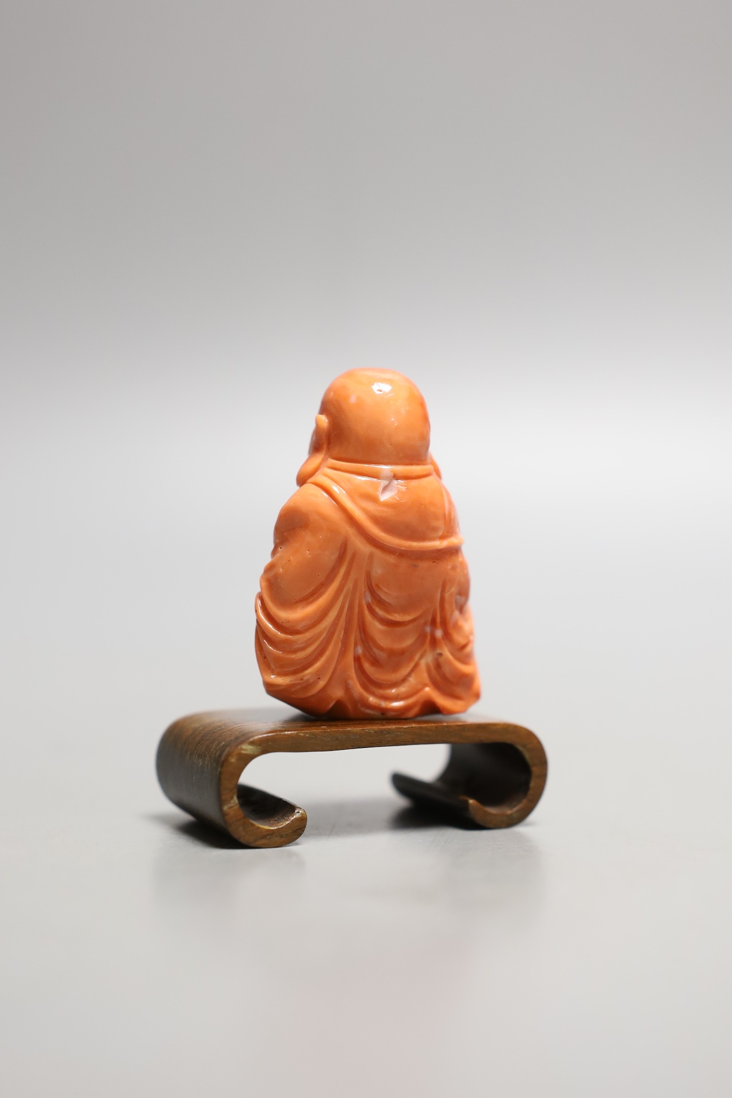 A Chinese carved coral figure of Budai, 5cm excl wooden stand